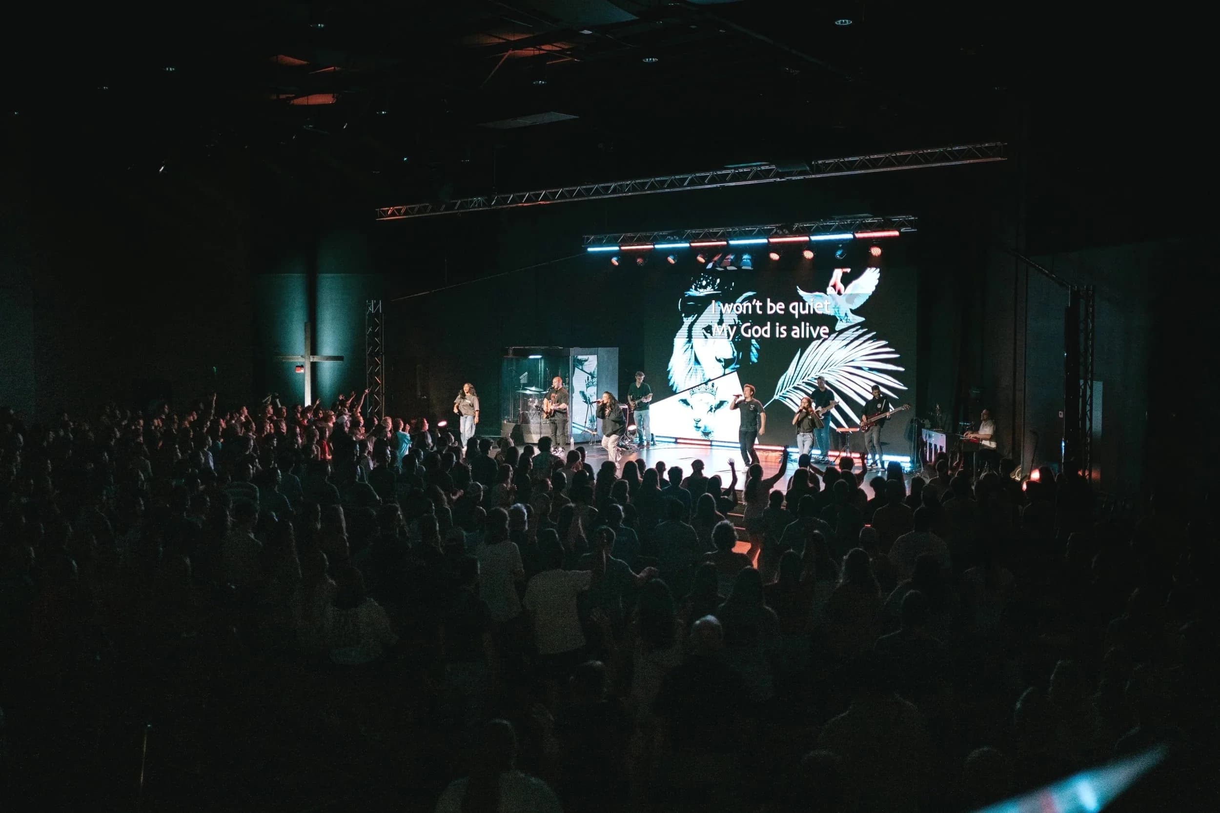 A packed room worshipping in front of a lit stage at a Generate gathering